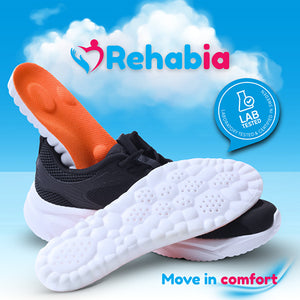 Oransje og hvite innleggssåler i sneakers med undersiden synlig, med skyer i bakgrunnen som formidler komfort og lett gange